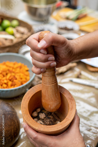 grinding cardamom, clove and traditional spice ingredient for jamu herbal drink photo