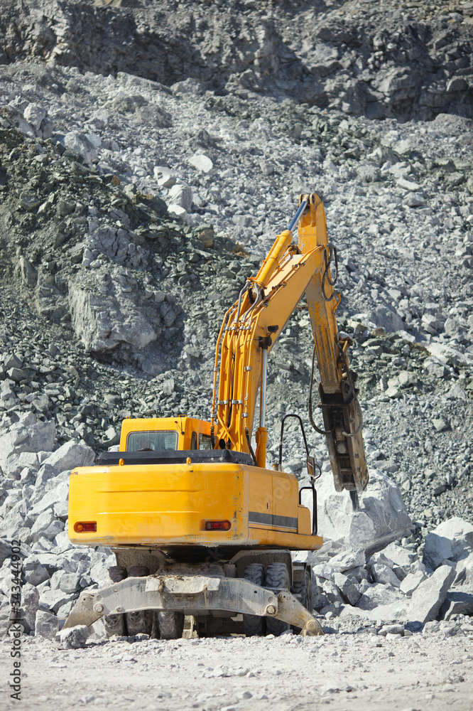 Hydraulic hammer crushes large stones in a stone quarry, back view, closeup. Heavy mining equipment. Hydraulic hammer crushes large stones in a stone quarry, back view, closeup. Heavy mining equipment.
