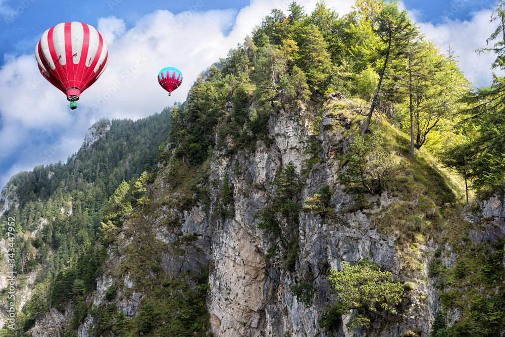 Red and white hot air balloons on background of high Alps mountains wth green forest under blue cloudy sky. Red and white hot air balloons on background of high Alps mountains wth green forest under blue cloudy sky.