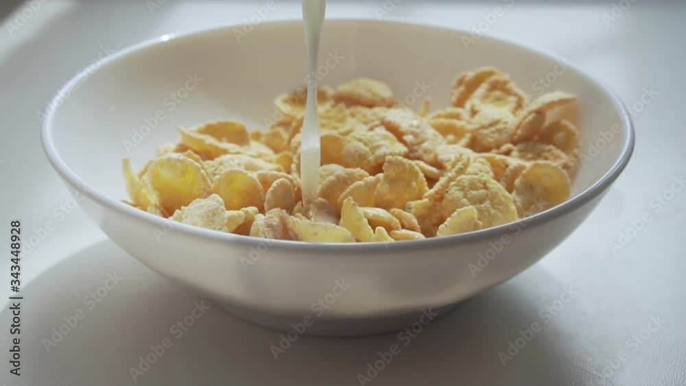 Pouring milk into the bowl with corn flakes. Pouring milk into the bowl with corn flakes.