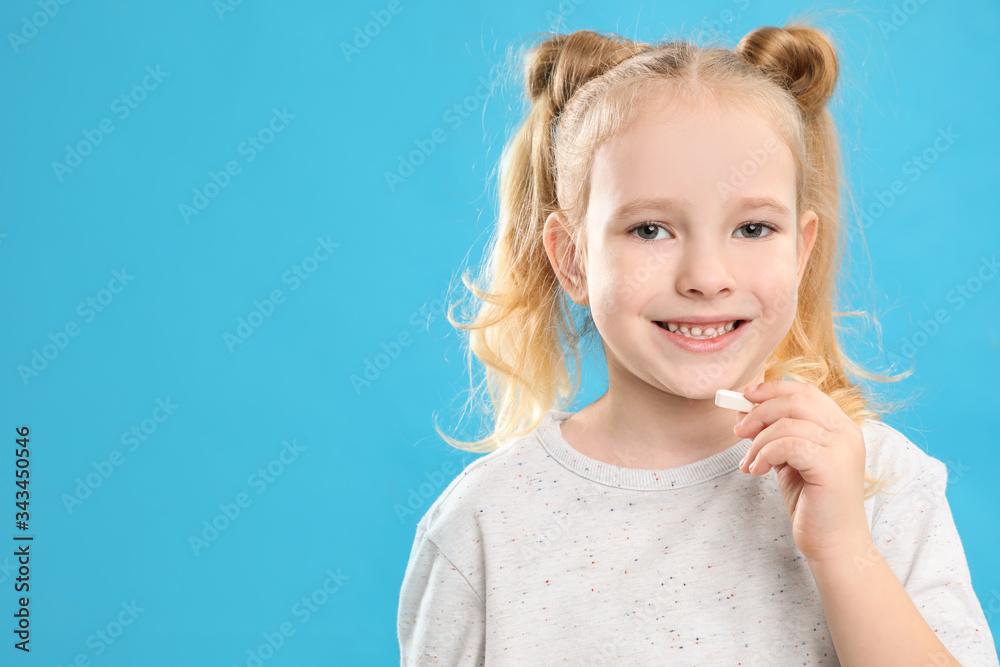 Little girl taking vitamin pill on light blue background. Space for text Little girl taking vitamin pill on light blue background. Space for text