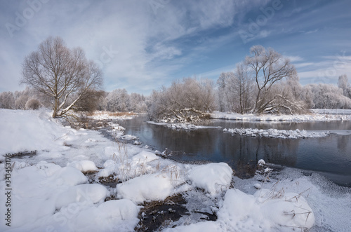 Winter Christmas Landscape In Blue Tones With Calm River, Surrounded By Trees. Landscape With Snowy Trees, Beautiful Frozen River With Reflection In Water And Ice Rim With Traces Of Wild Animals