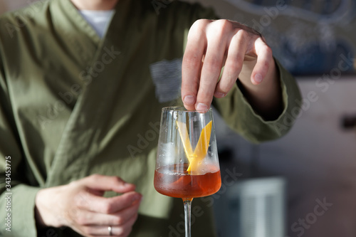 Male bartender is adding lemon zest to cocktail