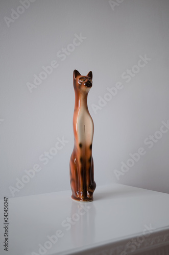 A ceramic statuette of a cat is on a table