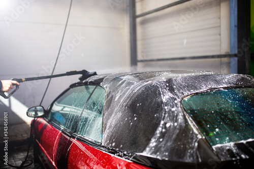 washing a red car convertible manually by brush with foam. photo