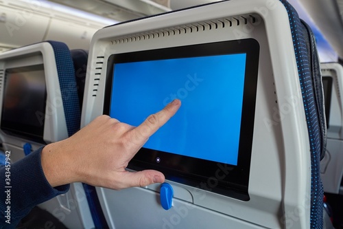 Using the seatback screen on a plane trip, watching movies, displaying flight data. Finger on blank touchscreen.