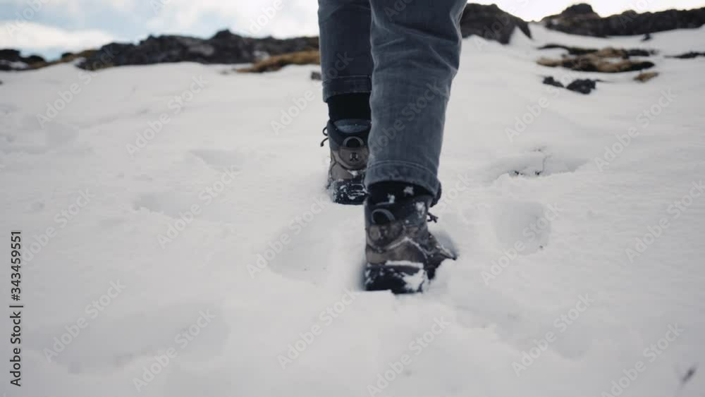 Person walking through snow and rocks towards vehicle on sunny day Person walking through snow and rocks towards vehicle on sunny day