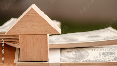 The model of a wooden house is stacked near the money dollar. Concept Having a house or buying a home or home loan.