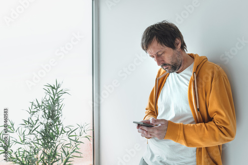Man with yellow zip hoodie using mobile phone in morning