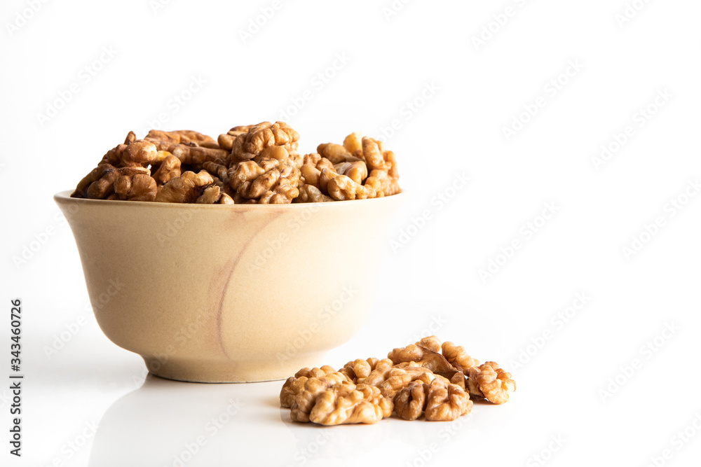 Walnut dry fruits in a brown bowl against a white background
