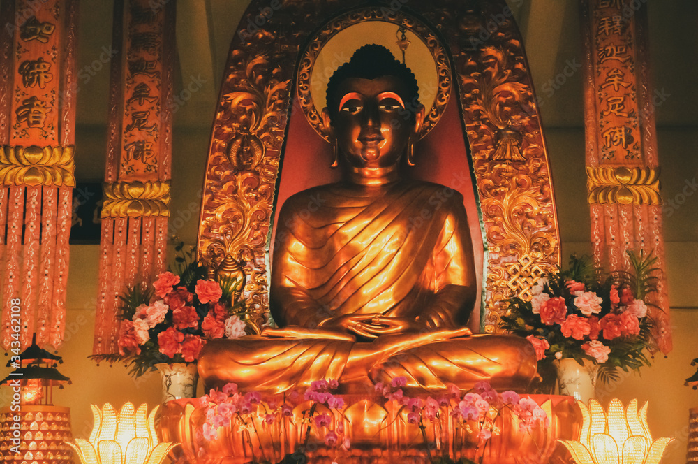 Golden Buddha statue on the floral altar. Lotus temple in Lantau island. Hong Kong
