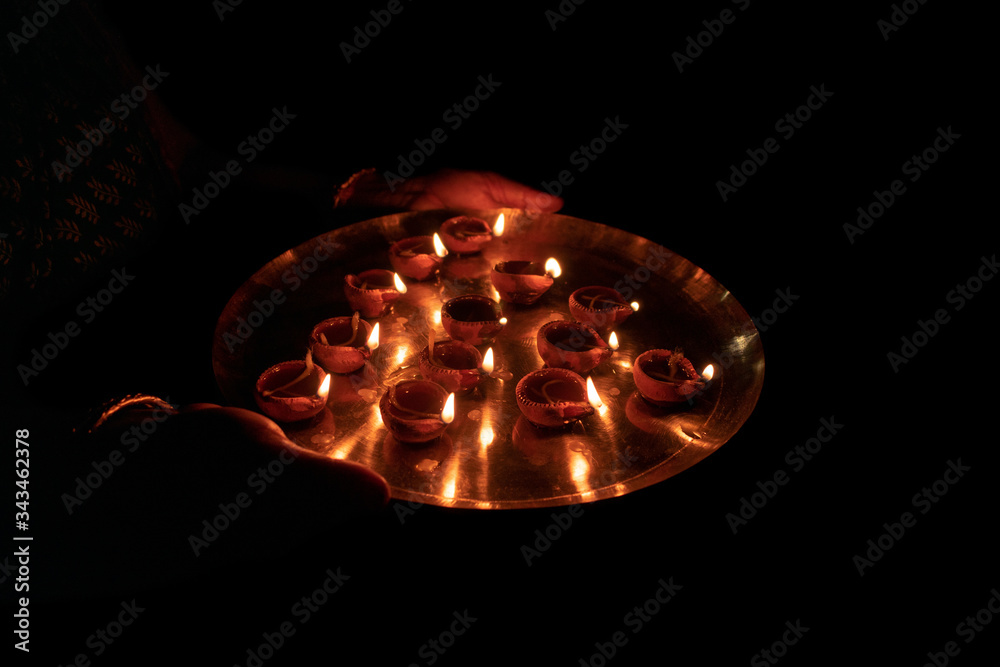 Indian woman performing worship along with lighting oil lamp