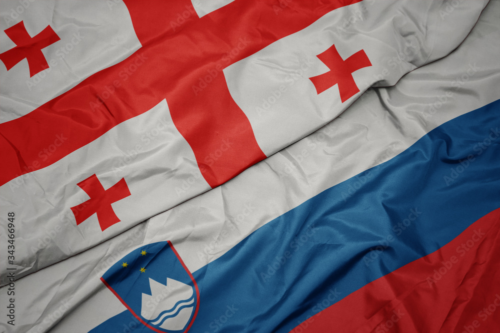 Fototapeta premium waving colorful flag of slovenia and national flag of georgia.
