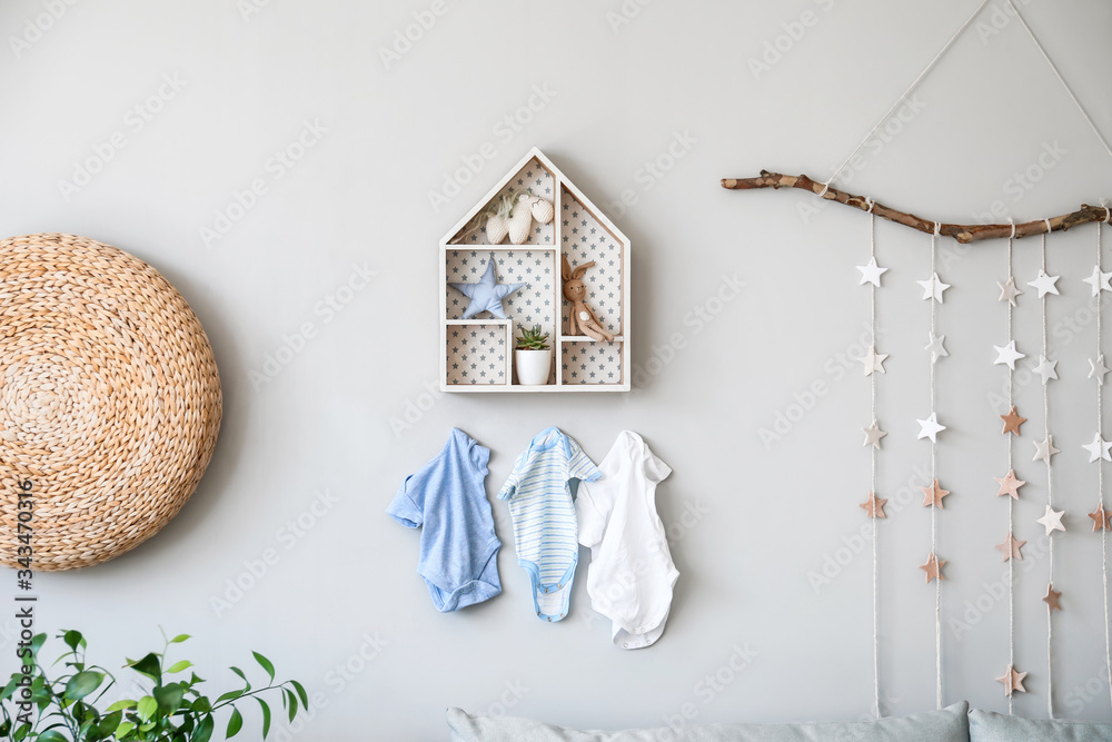 Stylish shelf with toys and clothes hanging on wall in children's room - obrazy, fototapety, plakaty 