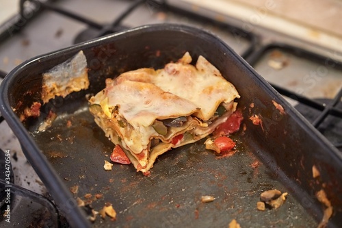 Fotografie Lasagne leftover food in a pan on a dirty kitchen stove