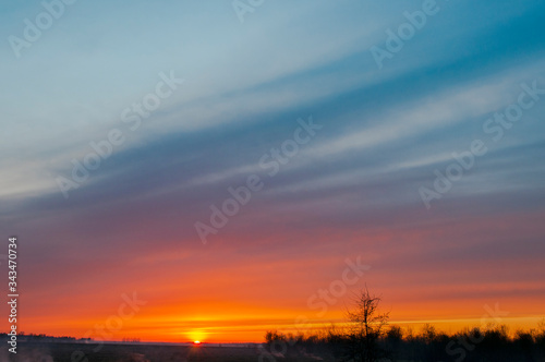 Panorama of dawn fire in the sky above the natural pasture. Golden red clouds just before sunrise. Picturesque landscape at sunrise. Beauty in nature © mikhailgrytsiv