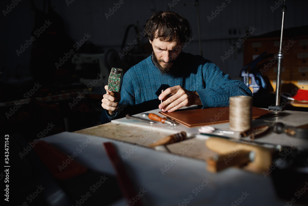A leather craftsman works in a workshop. A leather craftsman works in a workshop.