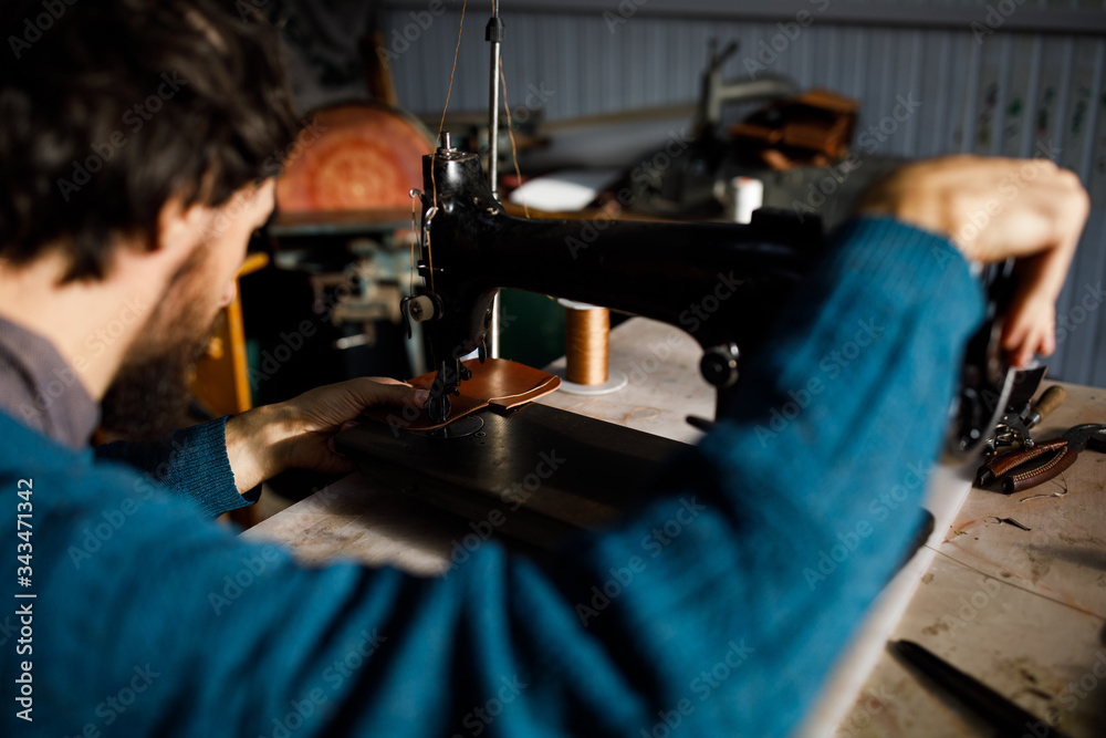 A leather craftsman works in a workshop. 