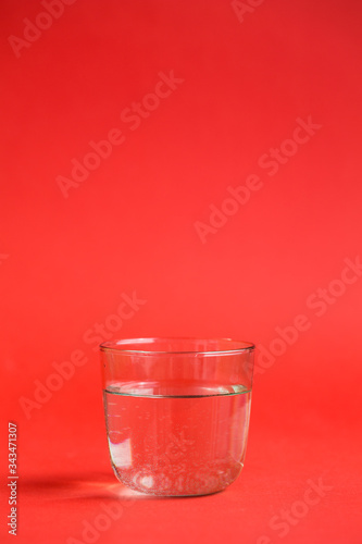 Obraz na płótnie Transparent glass of water on a red background w salonie