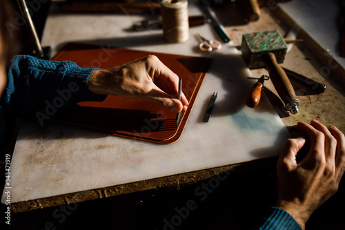 A leather craftsman works in a workshop. 