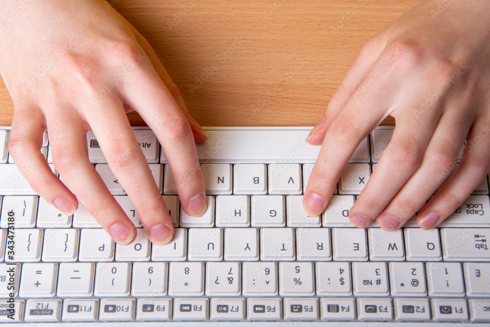 two female hand is typing on a white keyboard with English letters. The concept of home schooling, distance learning two female hand is typing on a white keyboard with English letters. The concept of home schooling, distance learning