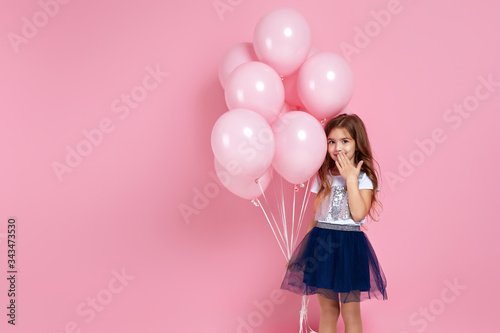 cute little child girl with pastel pink air balloons covering his mouth with hand isolated over pink background. OMG. kid forgot a gift for birthday party. copy space