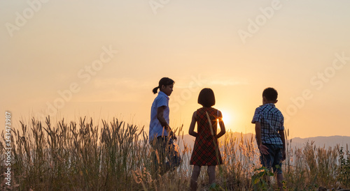 Silhouette of children playing on mountain at sunset background
