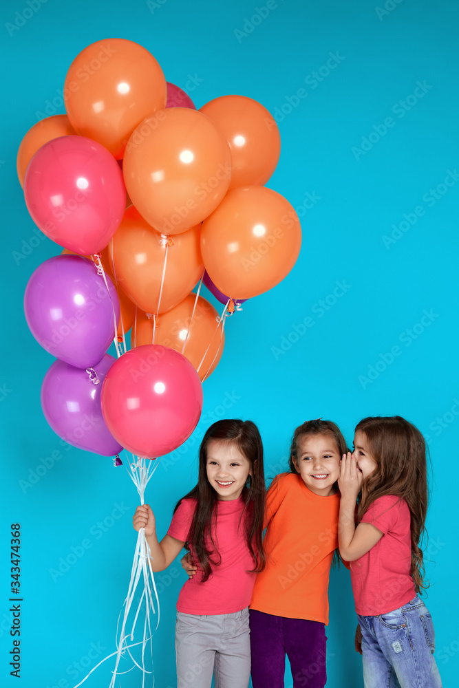 Φωτογραφία Smiling little children girls posing with bright colorful air balloons on blue background