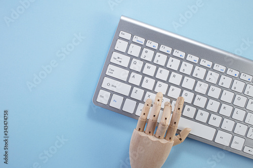 Keyboard of laptop on blue background, minimal style. Workspace with a wooden hand, laptop. Business desk minimal and modern style concept. Flat lay