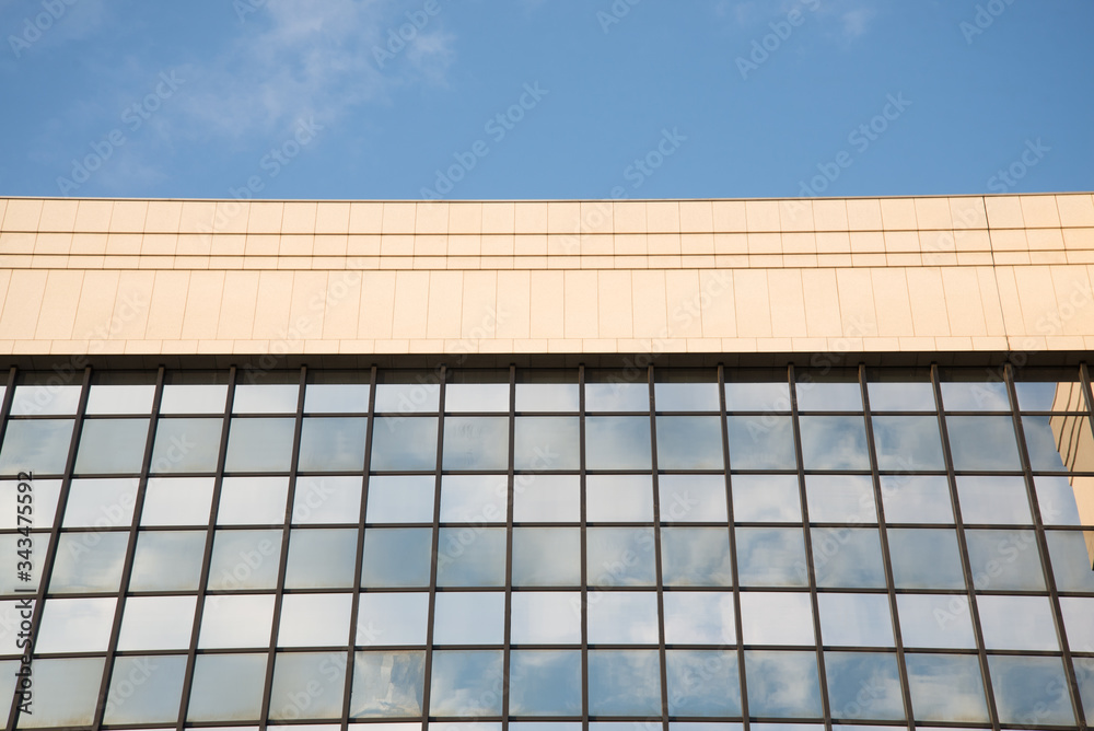 Facade of a modern building with windows mirroring the sky and the clouds Facade of a modern building with windows mirroring the sky and the clouds