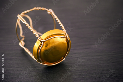 Champagne muselet with golden cap on black stone background