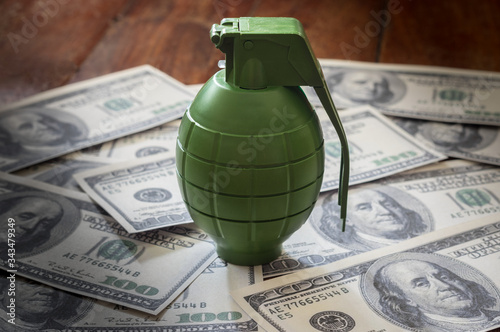 Green plastic toy grenade on money bills.