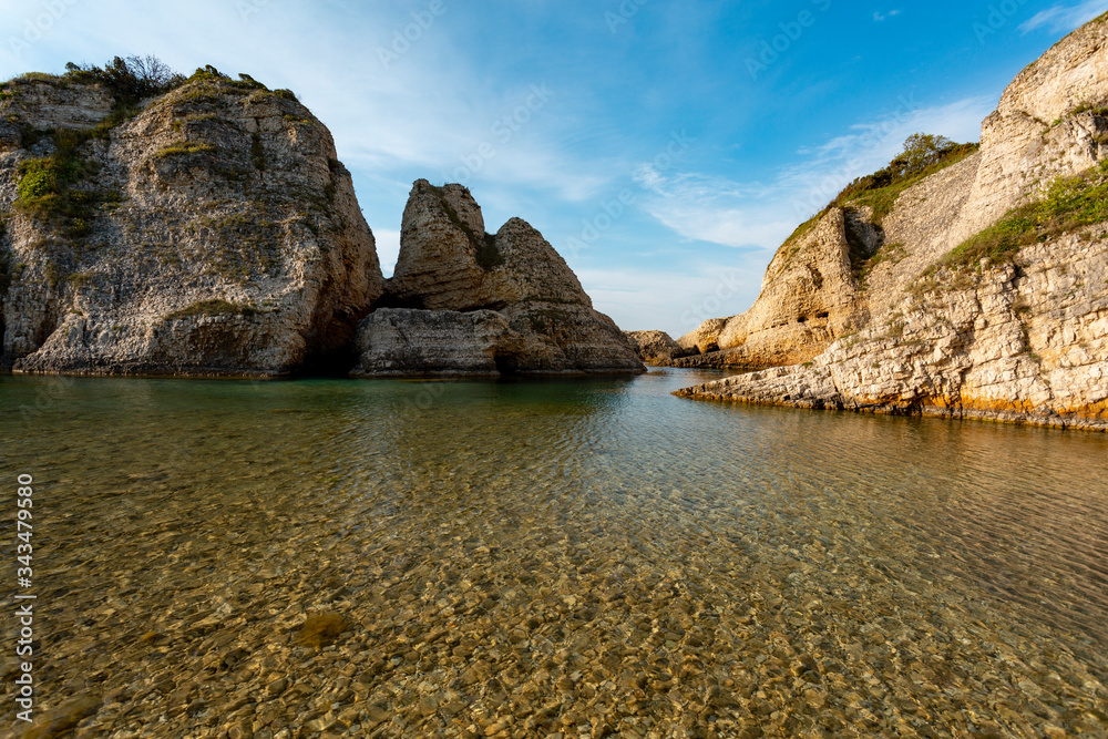 Stone mountains and blue sky in front of the sea.