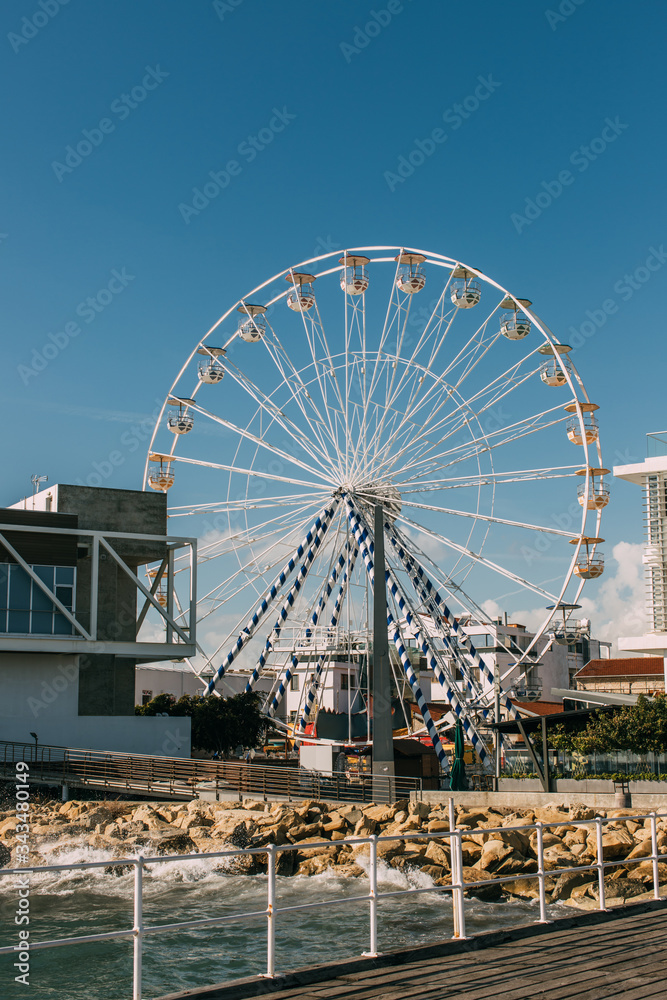 ferris wheel near building and mediterranean sea