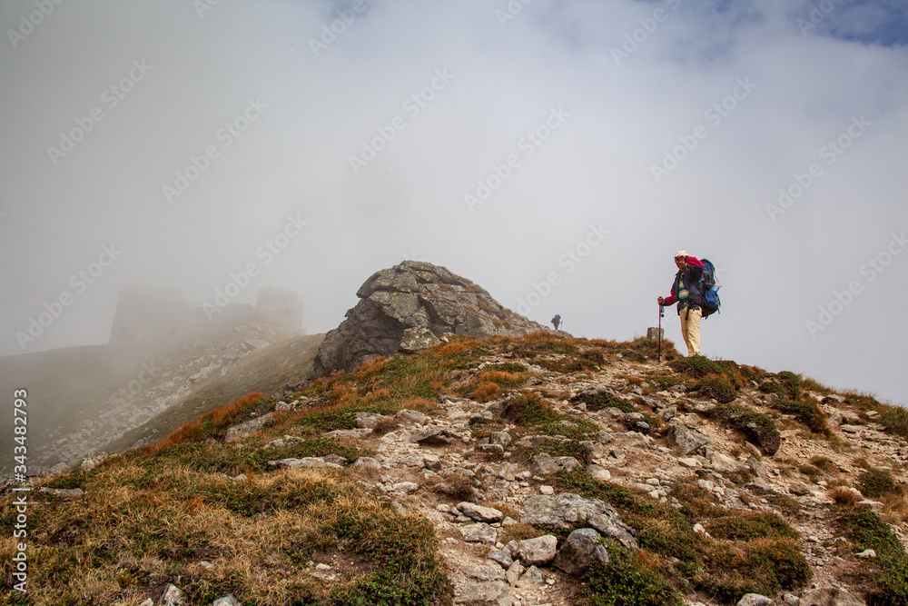 Hiker with backpack going uphill. Hiker going up to the mountain peak on a very steep trail.