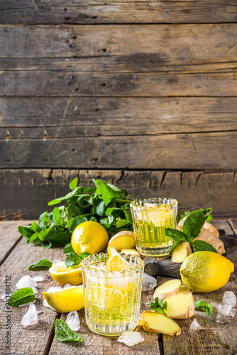 Homemade ginger lemonade cocktail. Cold summer ginger lemon ale. Sweet and sour iced refreshing beverage with lemon slice garnish,  Detox and weight loss drink concept. Wooden rustic background copy s photo