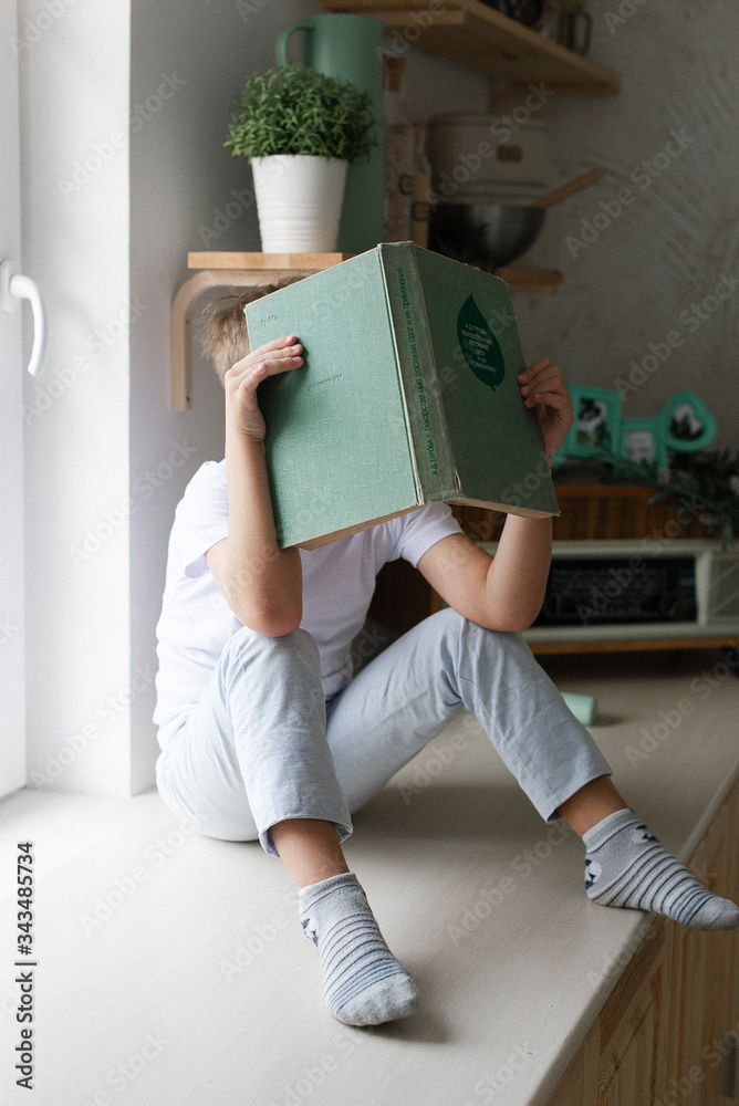 The boy is hiding behind a book. The child is tired of learning. The boy is hiding behind a book. The child is tired of learning.