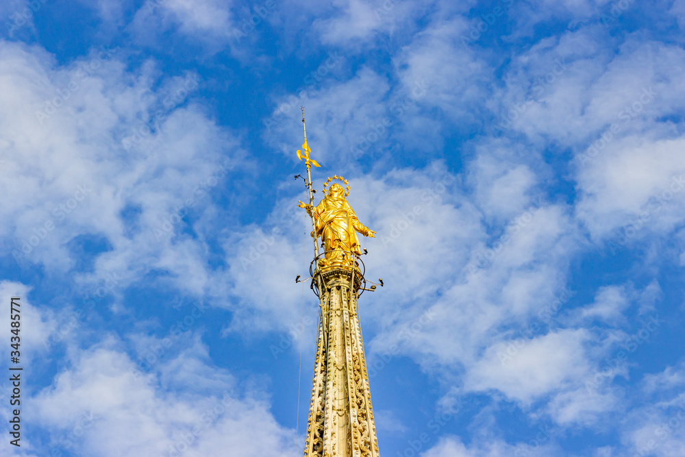 Fototapeta premium The gilded statue on the roof of Cathedral of Milan - Duomo di Milano in Milan, Italy