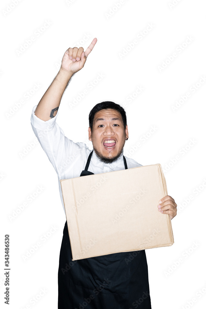 Bearded asian men waiter, chef dressed in black apron is holding cardboard and showing point finger in white background.The concept of protest. Place for text or copy space. Clipping path. Bearded asian men waiter, chef dressed in black apron is holding cardboard and showing point finger in white background.The concept of protest. Place for text or copy space. Clipping path.