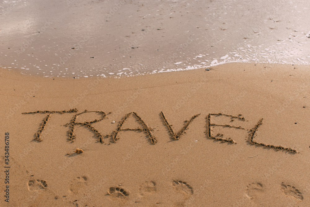Fototapeta premium summer beach with travel lettering on sand near sea