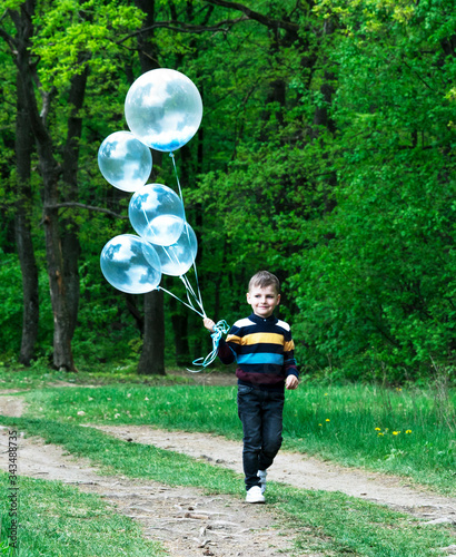 boy with balloons in the green forest