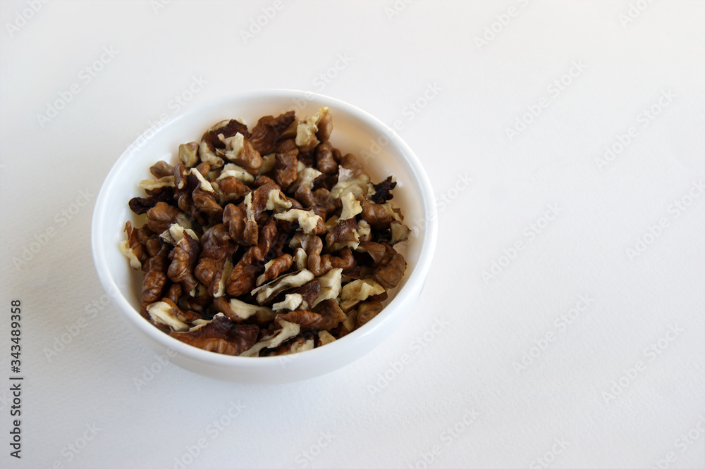 Peeled walnuts in a white cup on a white table Peeled walnuts in a white cup on a white table