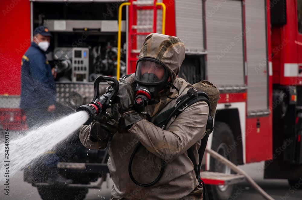 Obraz premium The savior of the fire service disinfects the streets of the city. Preventive methods against coronavirus. Specialist in hazmat suits cleaning disinfecting coronavirus cells epidemic, pandemic health 