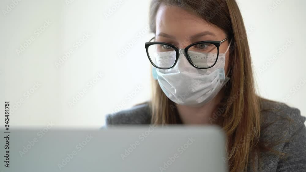 Young woman working at laptop computer in office mask during epidemic covid-19 Young woman working at laptop computer in office mask during epidemic covid-19