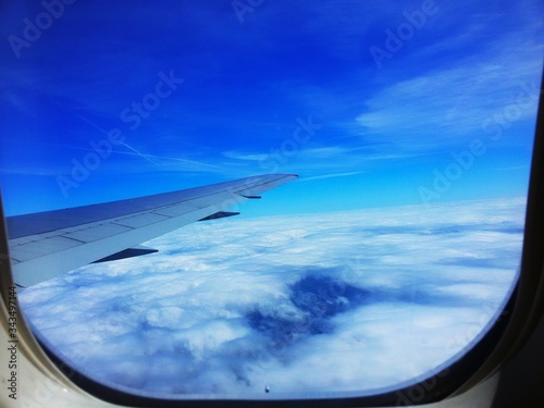 Beautiful view of white clouds and blue sky from an airplane porthole.