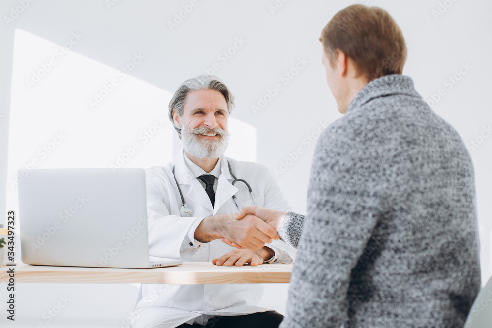 Senior doctor shaking hands with patient while meeting at doctor's office. Senior doctor shaking hands with patient while meeting at doctor's office.