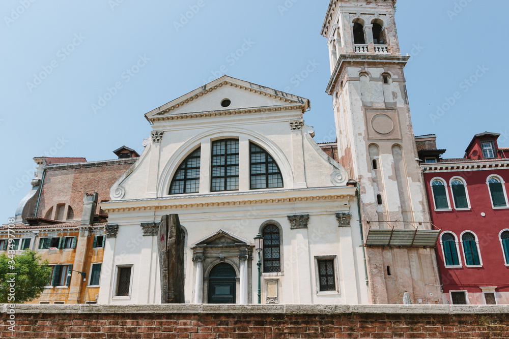 San Trovazo church. White wall and tower. Traditional facade of kirk in Venice, Italy. Nobody in sunny day. Summer time. Ancient building. Little venetian chapel. Walking along canal. Travel photo.