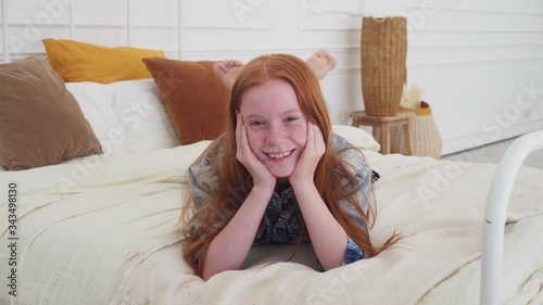 Funny red-haired girl with freckles smiling on bed