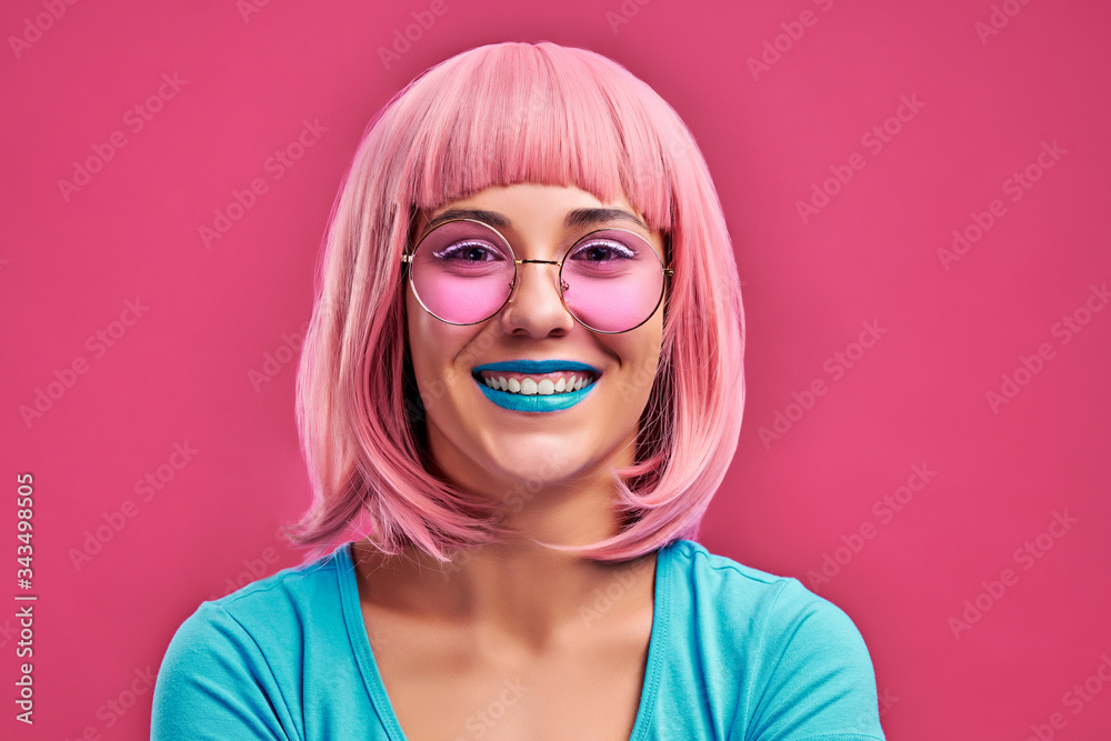 Young woman with pink hair and sunglasses have bright makeup isolated pink background