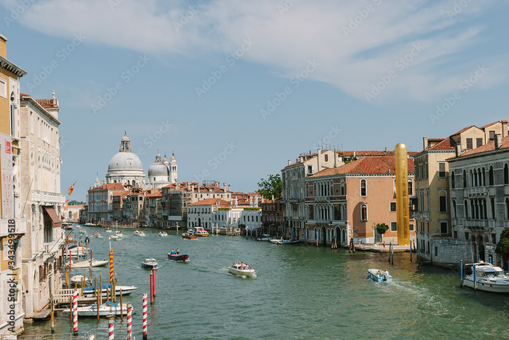 Street of Venice in summer time. Italian view. Roof, sea canal, boat in sunny day. Old city, ancient buildings.  Italy. Basilica Santa Maria della Salute. Popular tourist destination of Italy. Europe.